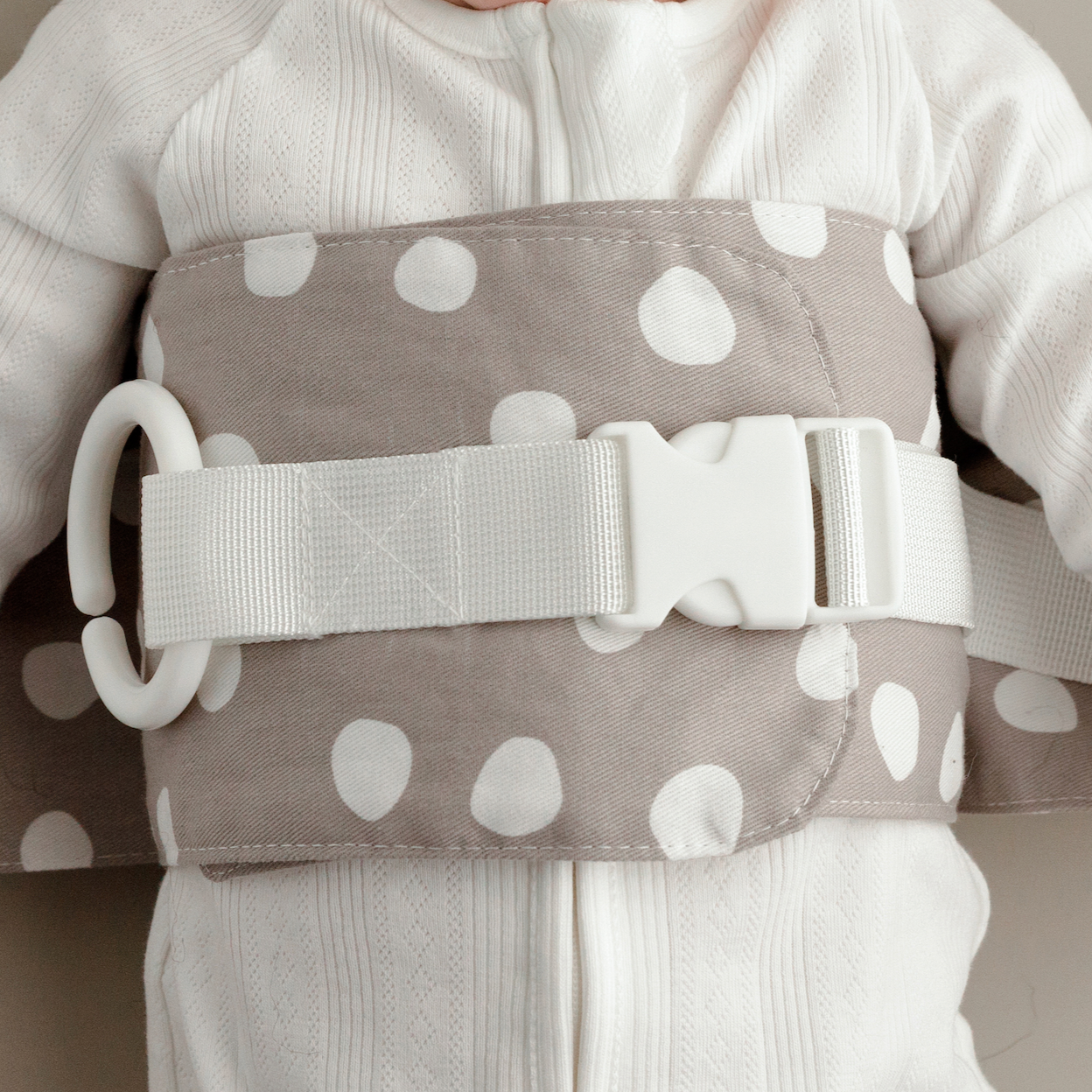 Close up of the grey and white Spotty Dotty WriggleBum nappy change harness with white straps and buckle