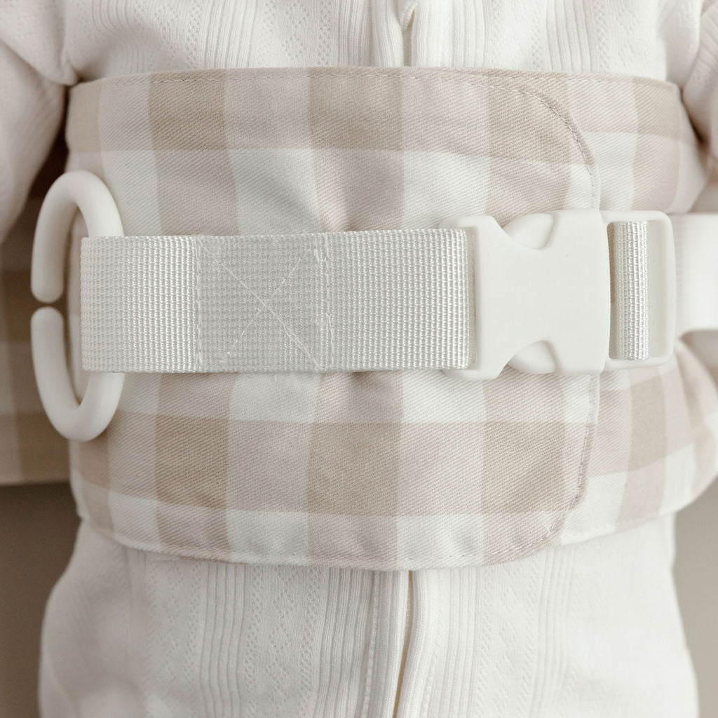 Close-up of the beige gingham WriggleBum nappy change harness with a white strap and buckle.