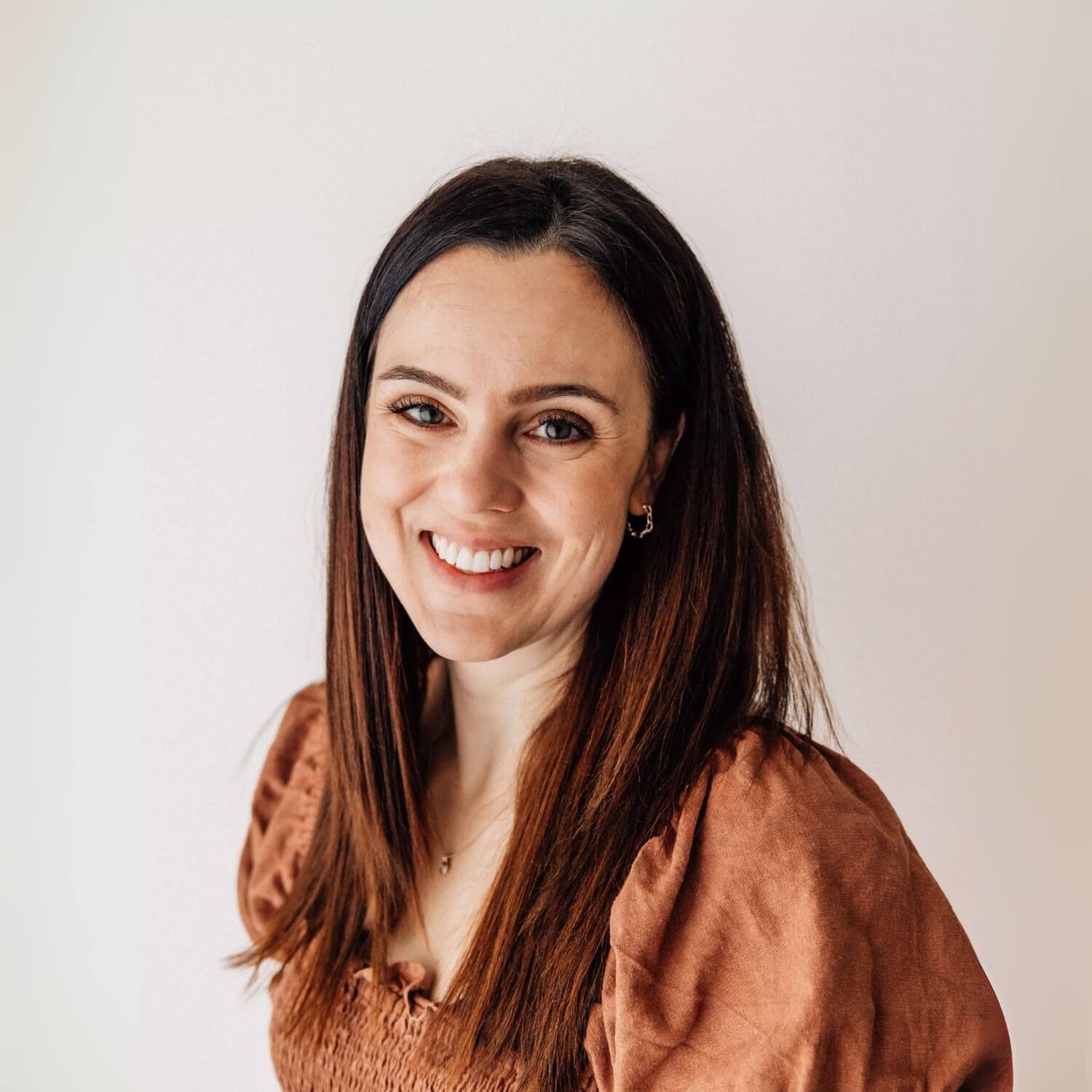 A woman with long brown hair is smiling. Beck is the founder of WriggleBum nappy change harness.