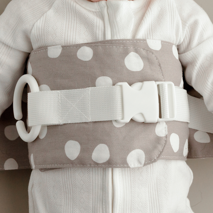 Close up of the grey and white Spotty Dotty WriggleBum nappy change harness with white straps and buckle
