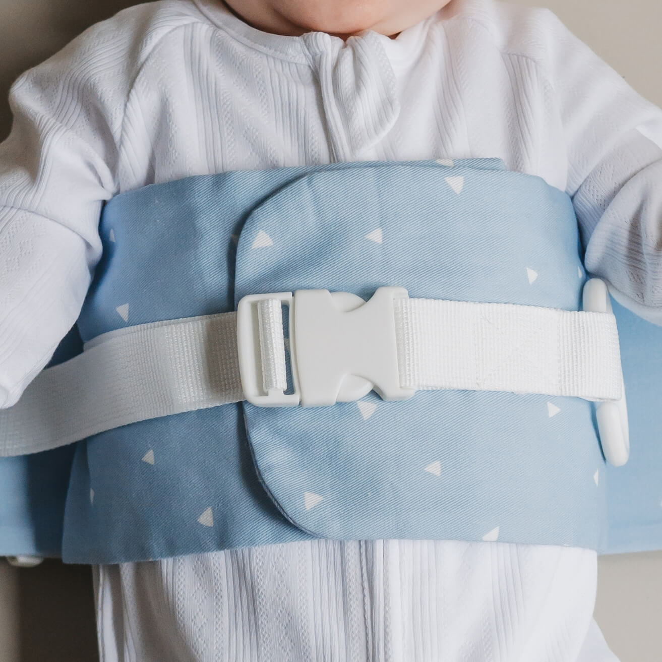 A close up of the Breezy Blue WriggleBum nappy change harness wrapped around a baby. 