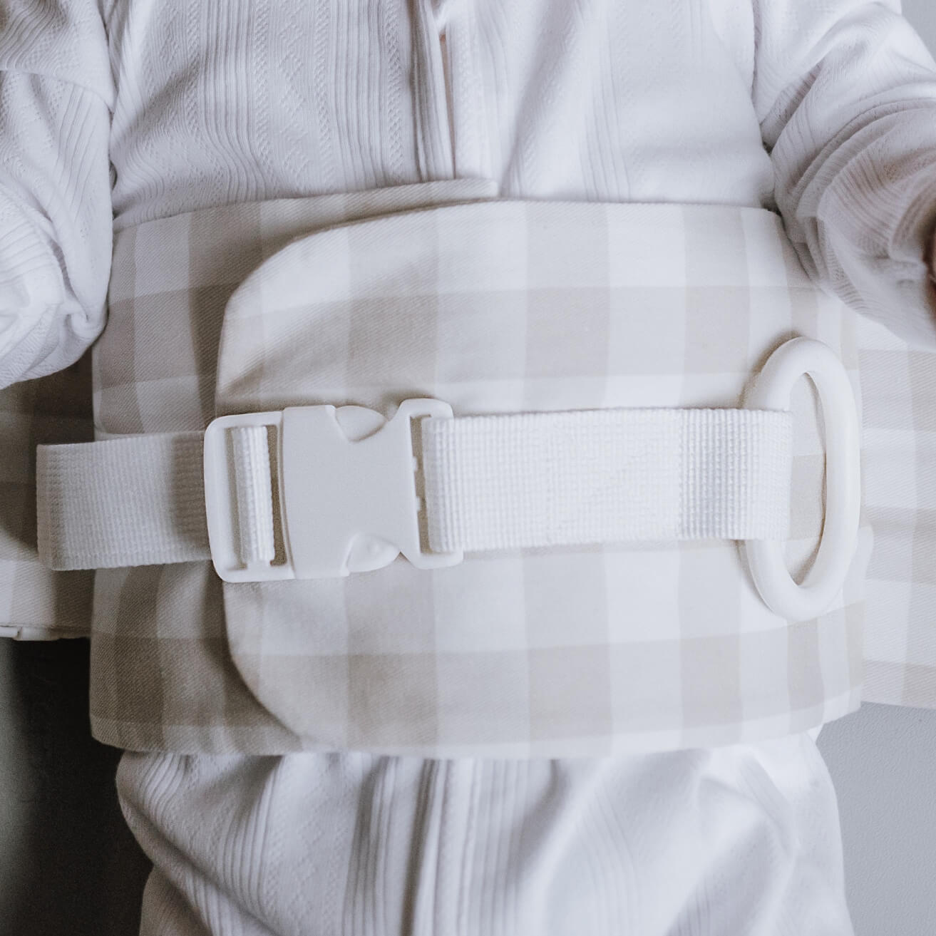 A close up of the Oatmeal Afternoon WriggleBum nappy change harness, wrapped around a baby.